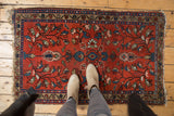 Vintage Lilihan rug corner showcasing cherry red field, blue-beige borders, and worn fringe.