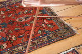 Lilihan rug corner: cherry red ground, blue floral border, low pile, and tattered fringe.