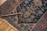 Worn corner of a Vintage Kurdish Hamadan rug with tattered fringe and navy, terracotta Herati motifs.
