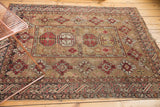 Antique Caucasian rug with pale bronze field, wine red geometric guls, and abstract people motifs.