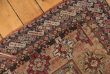 Corner view of an antique Caucasian geometric rug, featuring repeating guls, intricate borders, and rich patina.