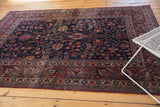 Meshed rug corner: wine red borders, sky blue motifs, and navy field with delicate tendrils.