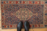 Antique Senneh rug corner: navy Herati field, oversized wine red border, mostly even wear.