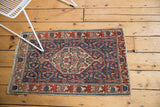 Antique Senneh rug's tattered fringe, navy Herati motif, and red oversized border.