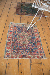 Angled view of an Antique Senneh rug, Herati motif, with tattered sides and ends.