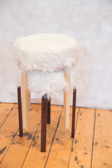 Alvar Aalto style stool's contrasting two-toned wooden legs and white faux fur texture.