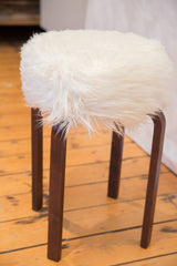 Straight dark brown wooden legs of the Alvar Aalto style stool.