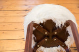Alvar Aalto style stool's dark wood base with brass fasteners and faux fur detail.