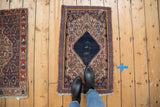 Vintage Senneh rug detail: navy medallion with Farsi script, Herati motif, and worn fringe.