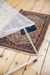 Vintage Senneh rug's intricate Herati motif, navy blue field, terra cotta border, and fringe wear.
