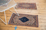 Vintage Senneh rug's tattered fringe and side edge, showcasing its navy and dusty gold Herati pattern.