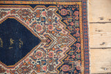 Vintage Persian Senneh rug's Herati pattern detail, navy, ivory, pale terra cotta, tattered edge.