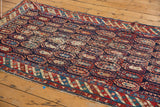 Antique Caucasian runner's navy field with playful, varied botehs and detailed striped border, showing localized wear.