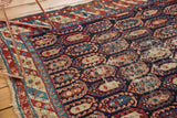 Antique Caucasian rug detail showing varied pile wear, navy field, and playful boteh motifs.