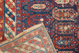 Hand-knotted foundation and wear visible on this antique Caucasian rug's navy and red pile.