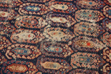 Antique Caucasian rug detail featuring stylized botehs, navy ground, and localized foundation wear.