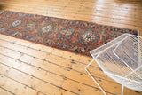 Angled long view of the Heriz runner, showing repetitive medallions in brick red and navy blue.