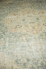Vintage distressed Tabriz carpet close-up, highlighting aqua and beige floral patterns with worn pile.