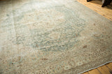 Distressed vintage Tabriz carpet corner featuring faded aqua green, beige, and brown floral designs.