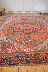 Vintage Heriz rug corner, madder red geometric vinery, and navy blue border patterns.