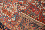 Folded corner of vintage Heriz rug, showing fringe, geometric motifs, and reverse foundation.
