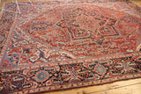 Vintage Heriz carpet showcasing low pile texture, geometric vinery, and abrashed cherry red and navy hues.