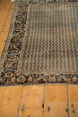 Antique Farahan Sarouk rug's intricate border and charcoal field with vertical wave pattern, showing low pile.