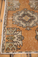 Distressed Oushak rug showing faded tangerine, ivory, brown motifs, even wear, and original selvage.