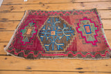 Playful hook and latch minor medallion with pink, blue, green on abrashed vintage Oushak rug.