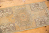 Distressed Oushak rug's muted roundel medallion, germinating plants, and visible knot wear.