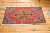 Distressed Oushak rug with a gold, brick red, and slate blue central geometric medallion.