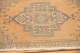 Distressed Oushak rug detail, showing geometric medallion, time-softened beige and pale blue, with worn texture.