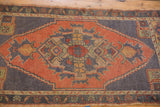 Even wear across the faded brick red medallion and dusty ink blue field of this vintage Oushak rug.