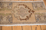 Close-up of vintage distressed Oushak rug: low pile, muted beige field, brown roundel, blue accents.