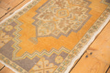 Vintage Oushak rug with faded gold field and geometric stepped floral border.