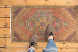 Distressed Oushak rug's European Rococo medallion, dusty blush, seafoam green, and worn pile.