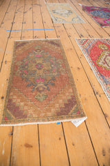 Angled view of distressed Oushak rug, showing even wear, blush, seafoam, and purple Rococo motifs.