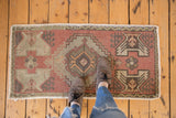 Vintage distressed Oushak rug corner, dusty brick and grey geometric field, intact selvage.