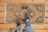 Vintage distressed Oushak rug mat showcasing faded apricot, charcoal medallion, and pink highlights.