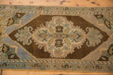 Ornate quatrefoil medallion with blossomed finials on distressed Oushak rug, bronze and blue tones.