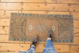 Vintage distressed Oushak rug's central geometric medallion and soft color palette.