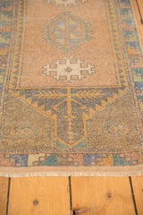 Visible light loss on the distressed fringe of a vintage Oushak rug mat.