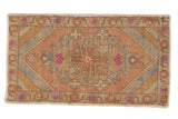 Vintage distressed Oushak rug mat featuring a central medallion, stylized florals, and striped spandrels with pops of bright pink, 1'8