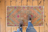 Distressed Oushak rug corner with striped spandrel, beige, gold, and pink floral motifs.
