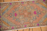 Distressed vintage Oushak rug showing visible wear, stylized pink floral motifs and muted beige.
