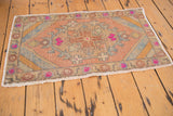 Distressed Oushak mat's secured end, fringe, and striped corner spandrel in blush and gold.