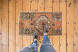 Distressed Oushak rug mat's diamond medallion and worn pile, styled with leopard shoes.