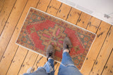 Distressed vintage Oushak rug with faded dusty blush, blue, and orange vine motifs.