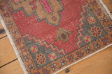 Distressed Oushak rug corner, showing stepped geometric border and intact selvage.
