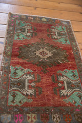 Distressed vintage Oushak rug detail: brick red field, mint green motifs, visible white knots.